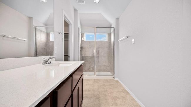 Bathroom with a stall shower, vanity, lofted ceiling, a walk in closet, and tile patterned flooring | Image 23