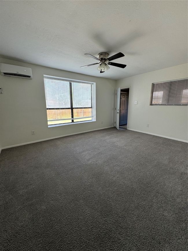 Empty room with an AC wall unit, ceiling fan, baseboards, and carpet | Image 17