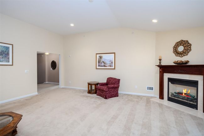 Living area with a fireplace with flush hearth, vaulted ceiling, light colored carpet, and recessed lighting | Image 12