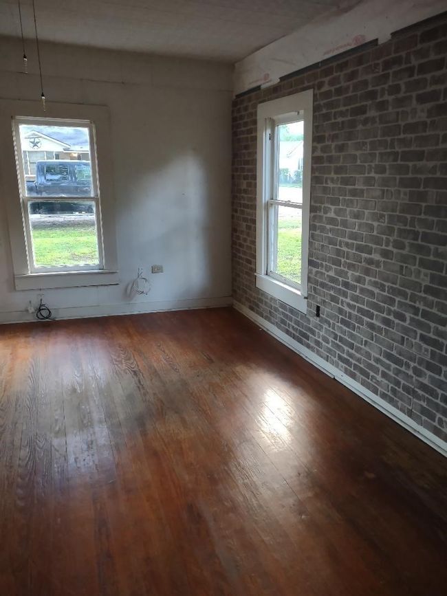 Empty room with hardwood / wood-style flooring, brick wall, and baseboards | Image 18