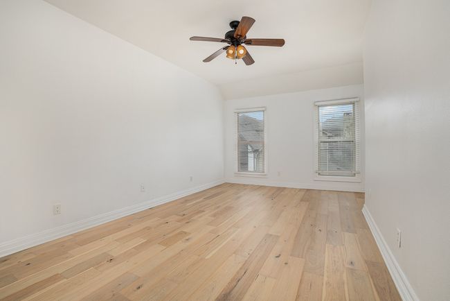 Empty room with light wood-style flooring, vaulted ceiling, ceiling fan, and baseboards | Image 15