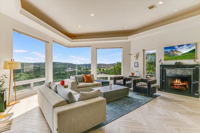 Living area featuring a raised ceiling, a premium fireplace, recessed lighting, and crown molding | Image 6