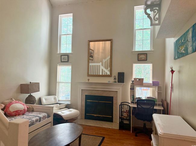 Living room featuring a towering ceiling, wood finished floors, and a tiled fireplace | Image 7