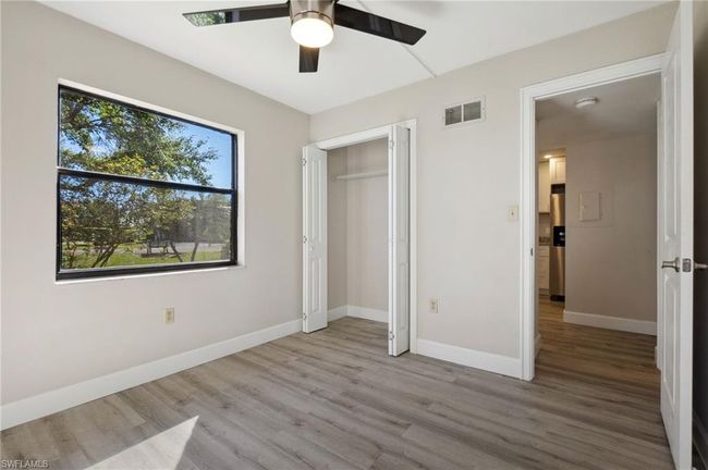 Unfurnished bedroom with ceiling fan, light wood-type flooring, stainless steel refrigerator with ice dispenser, and a closet | Image 7