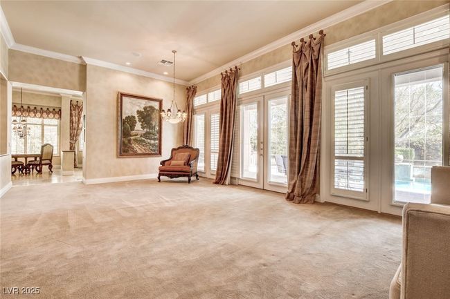 Sitting room with an inviting chandelier, crown molding, light carpet, baseboards, and french doors | Image 7