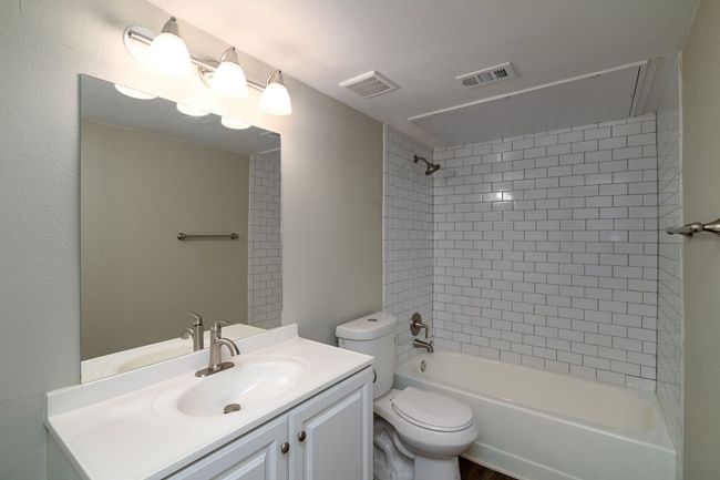 Full bathroom featuring toilet, visible vents, washtub / shower combination, and vanity | Image 12