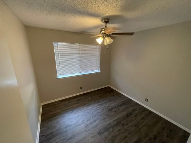 Empty room with ceiling fan, dark wood-style flooring, and a textured ceiling | Image 6