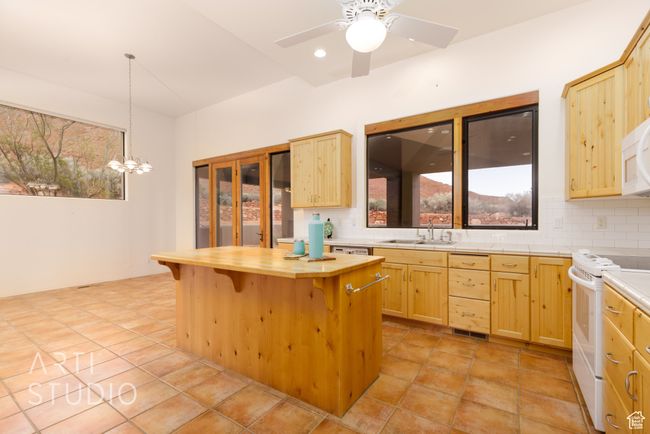Kitchen with a kitchen breakfast bar, tasteful backsplash, white electric range, a sink, and light brown cabinets | Image 22