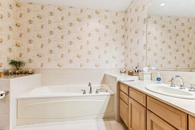 Bathroom with wallpapered walls, vanity, tile patterned floors, and a bath | Image 17