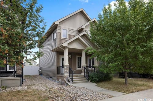 Front exterior featuring multi-toned siding, a covered porch with stone-clad pillars, and a concrete walkway | Card Image