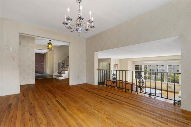 Spare room with stairs, hardwood / wood-style flooring, and a notable chandelier | Image 9
