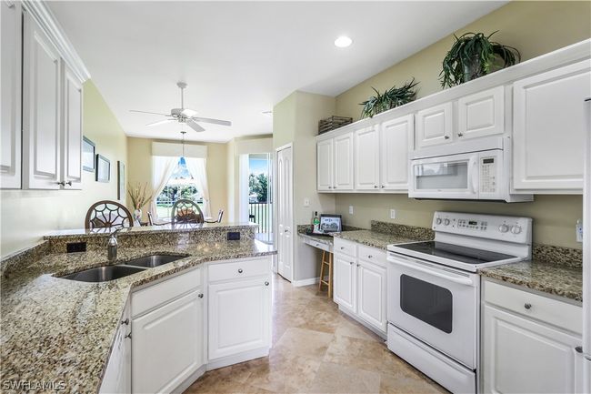 Kitchen featuring white appliances, white cabinets, granite countertops and light tile floors | Image 9