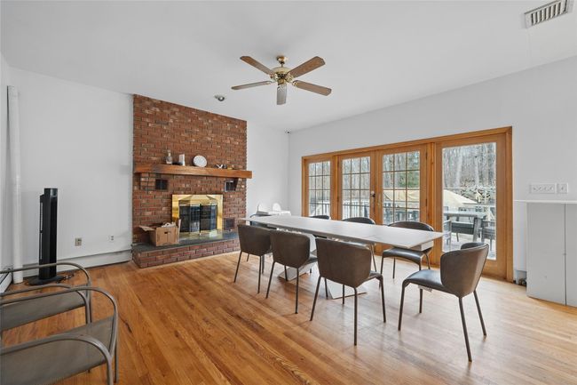 Dining area featuring visible vents, light wood-style floors, a ceiling fan, a brick fireplace, and baseboard heating | Image 6