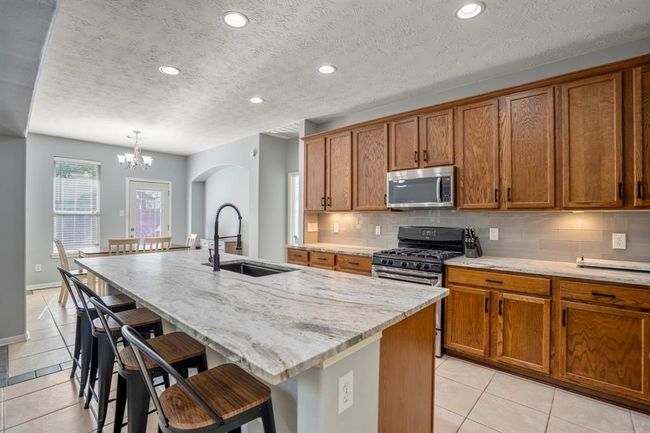 Another angle of the kitchen highlights the striking leathered granite counters and the warm glow of under-cabinet lighting—both functional and stylish touches that elevate the space. | Image 11