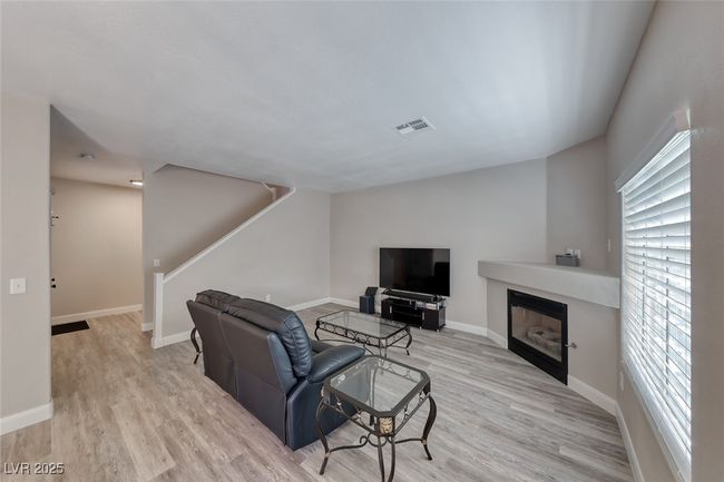 Living area with light wood-style floors, plenty of natural light, stairway, and a glass covered fireplace | Image 8