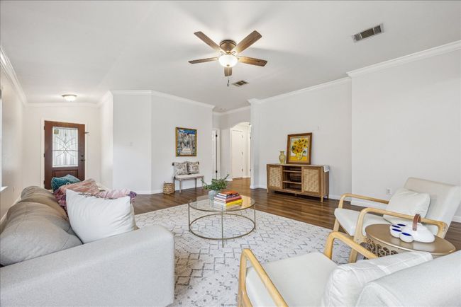 Living room with view of arched walkway to the bedrooms, featuring ceiling fan, crown molding | Image 5