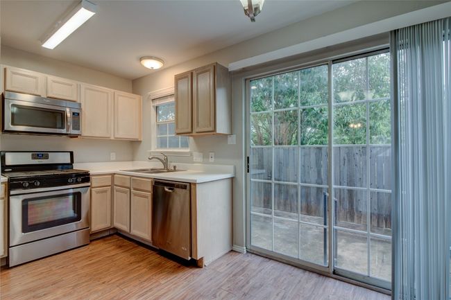 Kitchen featuring stainless steel appliances, a sink, light countertops, and light wood-style flooring | Image 13
