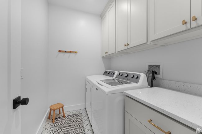 Washroom featuring cabinet space, washer and clothes dryer, and light tile patterned floors | Image 22