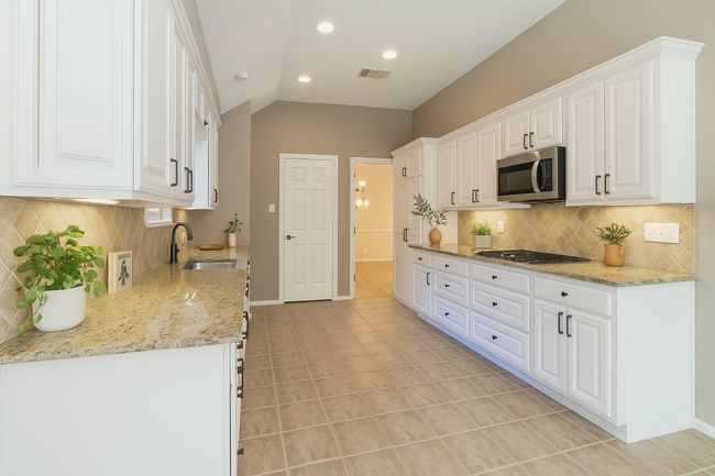 Kitchen with visible vents, appliances with stainless steel finishes, white cabinetry, and a sink | Image 14