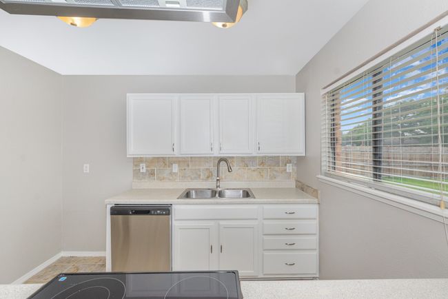 Kitchen with stainless steel dishwasher, white cabinetry, and light countertops | Image 7