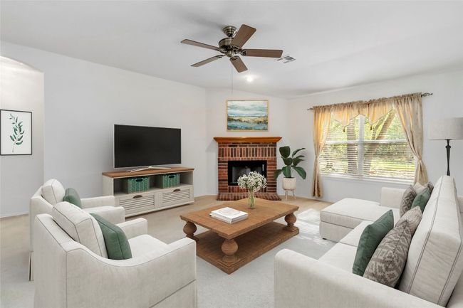 **Virtually Staged** Living area with ceiling fan, light carpet, arched walkways, and a fireplace | Image 11