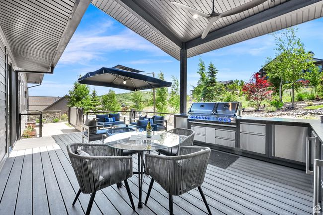Wooden deck with a ceiling fan, outdoor lounge area, and outdoor dining area | Image 60