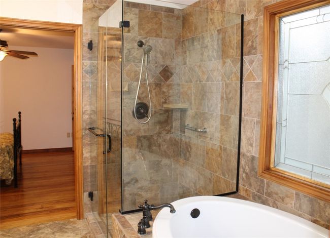 Bathroom with a shower stall, a garden tub, a ceiling fan, and baseboards | Image 18