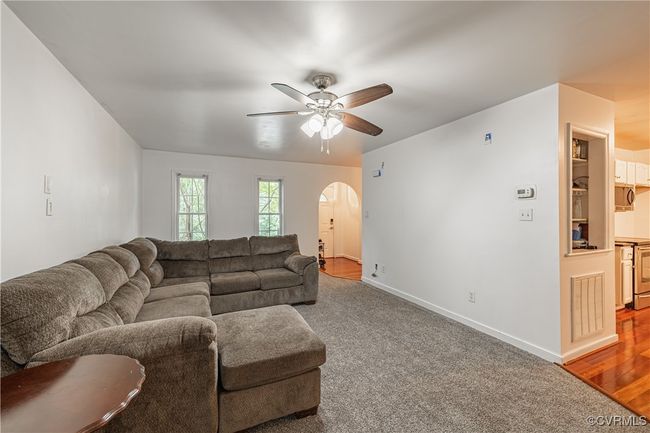 Carpeted living area with arched walkways and a ceiling fan | Image 9
