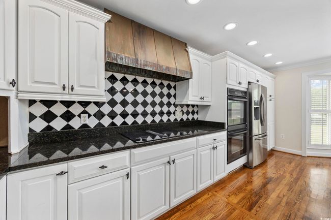 Kitchen with black appliances, recessed lighting, backsplash, white cabinets, and ornamental molding | Image 17