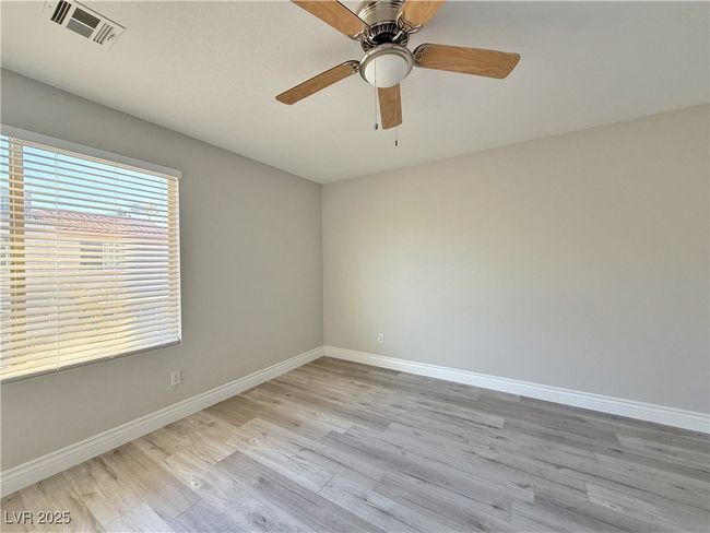 Empty room with light wood finished floors, visible vents, ceiling fan, and baseboards | Image 28