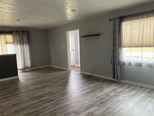 Empty room with healthy amount of natural light, wood finished floors, and baseboards | Image 6