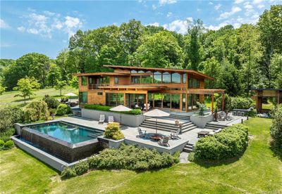 View of pool featuring a patio area, an outdoor hangout area, and a lawn | Image 1