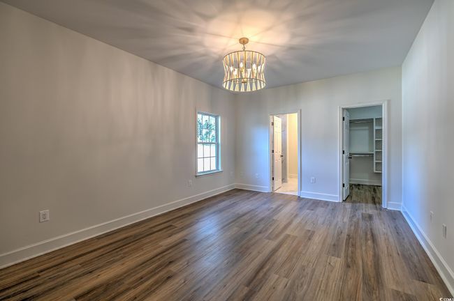 Unfurnished bedroom with a chandelier, dark wood-style floors, and a spacious closet | Image 13