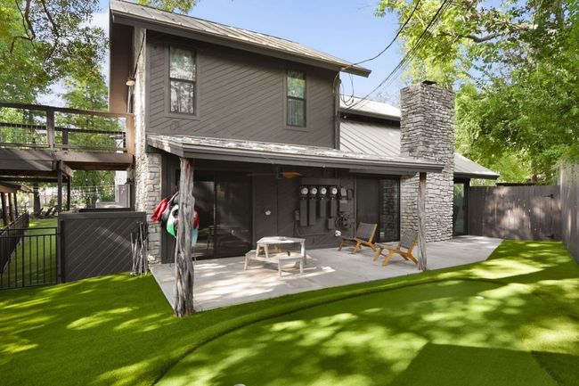 Back of property featuring stone siding, a fenced backyard, metal roof, and a patio | Image 35