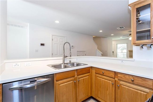 Kitchen featuring stainless steel dishwasher, light countertops, glass insert cabinets, recessed lighting, and ceiling fan | Image 7