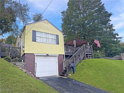 View of front of house featuring a front yard, a garage, and a wooden deck | Image 1