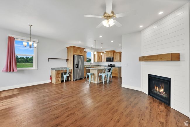 Living area with dark wood finished floors, recessed lighting, a ceiling fan, a large fireplace, and a chandelier | Image 48