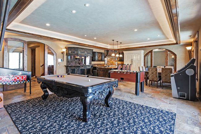 Playroom featuring a raised ceiling, arched walkways, ornamental molding, stone tile floors, and pool table | Image 50