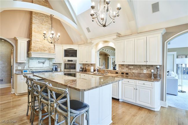 Bright and cheery kitchen with double ovens, Gas Range, island with sitting area, and hickory wood floors | Image 6
