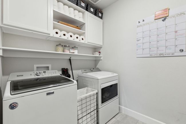 Laundry area with light tile patterned flooring, washing machine and clothes dryer, cabinet space, and baseboards | Image 19