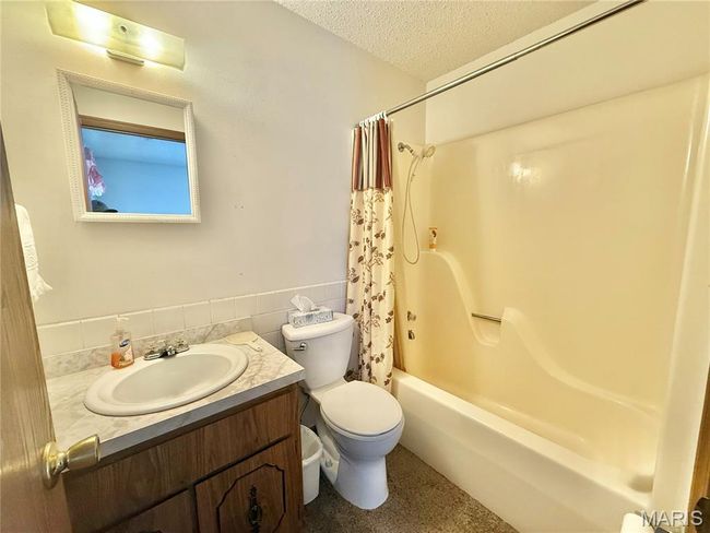 Bathroom with vanity, shower / bathtub combination with curtain, and a textured ceiling | Image 34