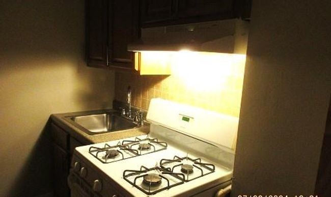 Kitchen featuring sink, decorative backsplash, stove, and wall chimney exhaust hood | Image 8