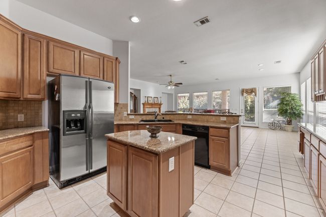 Kitchen featuring sink, stainless steel fridge with ice dispenser, kitchen peninsula, dishwasher, and a kitchen island | Image 18