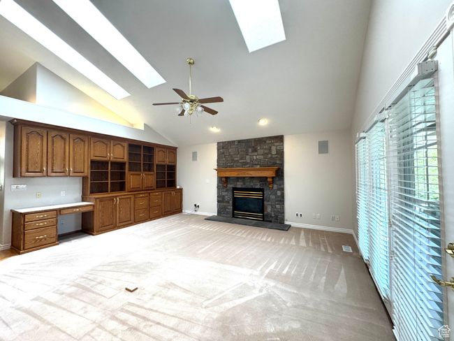 Great room with vaulted ceilings, sky lights, ceiling fan, gas fireplace and built-in cabinets. | Image 8