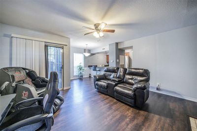 Living room with dark wood-type flooring, a textured ceiling, and ceiling fan | Image 1