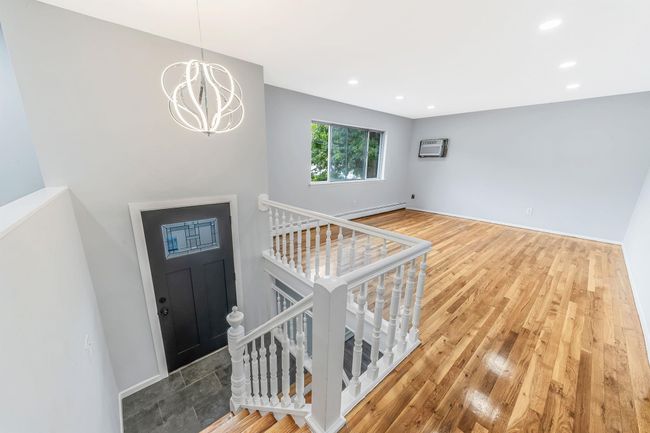 Entryway with wood finished floors, recessed lighting, a baseboard heating unit, an AC wall unit, and a notable chandelier | Image 4
