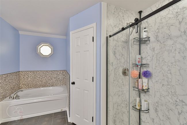 Bathroom with a bath, a stall shower, and tile patterned floors | Image 27
