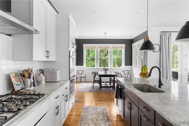 Kitchen with ventilation hood, a sink, stainless steel appliances, white cabinetry, and ornamental molding | Image 12