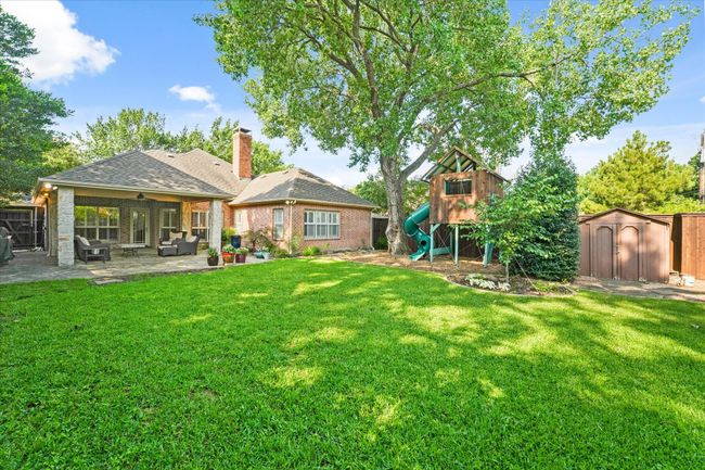 Rear view of house with a playground, a patio, an outdoor living space, a chimney, and brick siding | Image 34