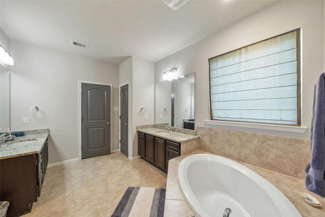 Luxurious bathroom with an elegant oval tub, separate shower, and dual sinks for convenience. | Image 19